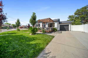 View of front of property with a pergola, concrete driveway, a garage, and painted brick