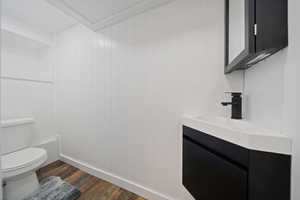 ADU Bathroom with wood finished floors, vanity, and wood walls
