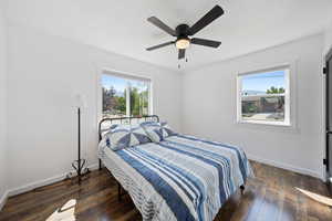 Bedroom featuring dark wood finished floors, multiple windows, and ceiling fan