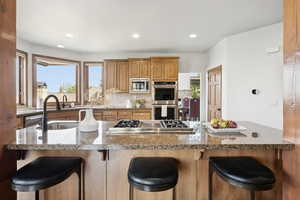 Kitchen with healthy amount of natural light, recessed lighting, appliances with stainless steel finishes, a breakfast bar area, and backsplash