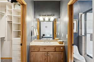 Full bath with a shower with shower door, ensuite bathroom, vanity, and a closet