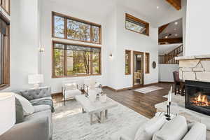 Living room with beam ceiling, wood finished floors, recessed lighting, a fireplace, and high vaulted ceiling