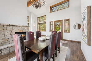 Dining room featuring high vaulted ceiling, wood finished floors, a chandelier, and a fireplace