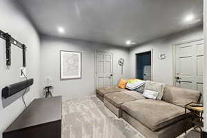 Living room featuring carpet flooring, recessed lighting, and a barn door