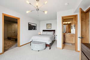Carpeted bedroom with a chandelier and connected bathroom