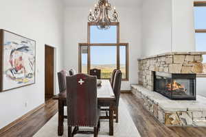Dining room featuring a high ceiling, a chandelier, wood finished floors, and a fireplace