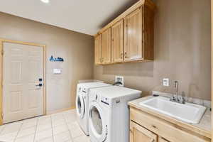 Washroom with independent washer and dryer, cabinet space, and light tile patterned floors