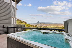 View of pool with a hot tub and a mountain view