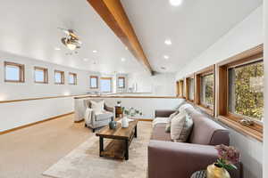 Living area with beam ceiling, recessed lighting, and light carpet