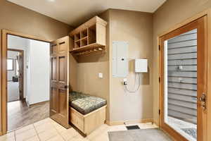 Mudroom with electric panel and light tile patterned floors