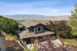 View of front of property featuring a shingled roof, a mountain view, and stone siding