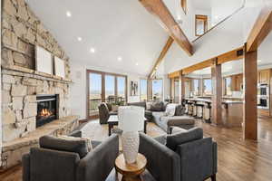 Living room featuring a fireplace, dark wood-style floors, beam ceiling, recessed lighting, and high vaulted ceiling