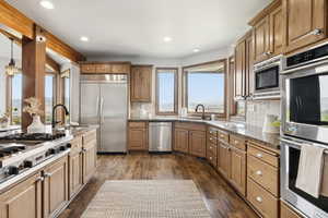 Kitchen featuring built in appliances, dark wood-style floors, decorative backsplash, recessed lighting, and dark stone countertops