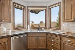 Kitchen featuring tasteful backsplash, dishwasher, healthy amount of natural light, and brown cabinets