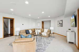 Living area with stairway, recessed lighting, and light carpet