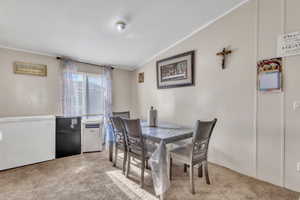 Dining room featuring light colored carpet, crown molding, and lofted ceiling