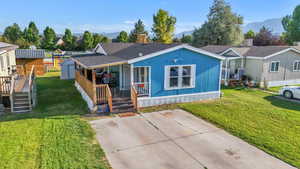 Manufactured / mobile home with covered porch, a mountain view, and a front lawn