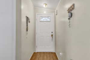 Doorway featuring light wood finished floors and ornamental molding
