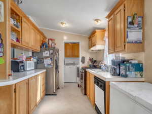 Kitchen with washing machine and dryer, stainless steel appliances, lofted ceiling, light countertops, and open shelves