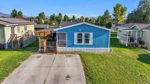 Manufactured / mobile home featuring a porch, a front lawn, a mountain view, and a residential view