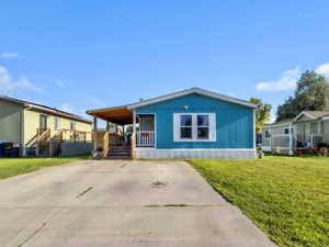 Manufactured / mobile home featuring covered porch, a front lawn, and driveway