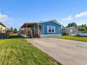 Manufactured / mobile home with a front lawn, a porch, driveway, and stairs