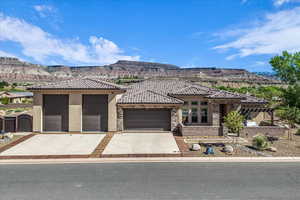 View of front of home with a mountain view, concrete driveway, stone siding, a garage, and stucco siding