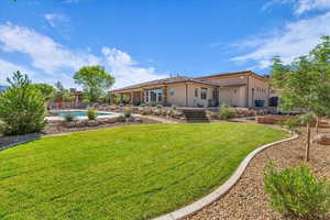 Rear view of house featuring stucco siding, an outdoor pool, and a yard