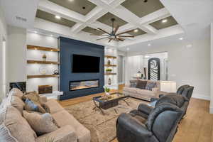 Living room featuring coffered ceiling, built in shelves, beamed ceiling, ceiling fan, and recessed lighting