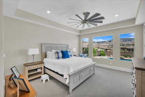 Bedroom with a raised ceiling, light carpet, recessed lighting, and a ceiling fan