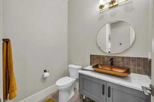 Half bathroom featuring vanity and decorative backsplash