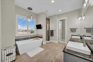 Bathroom with double vanity, a soaking tub, a stall shower, a chandelier, and recessed lighting