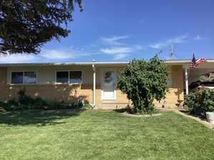 View of front of property with brick siding, a carport, and a front lawn