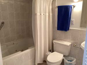 Full bathroom featuring tile walls and a combined bath / shower with jetted tub