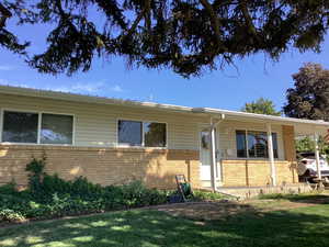 View of front facade featuring brick siding, a front lawn, and a carport
