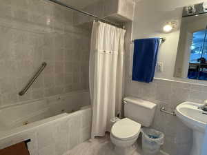 Full bath featuring tile walls and a combined bath / shower with jetted tub