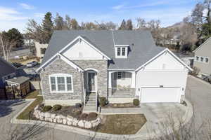 Craftsman-style house with a porch, stone siding, concrete driveway, and a shingled roof
