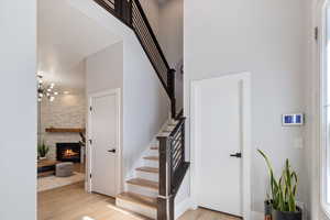Stairs featuring wood finished floors, a stone fireplace, and a high ceiling