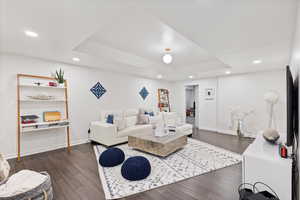 Living area featuring recessed lighting, dark wood finished floors, and a tray ceiling