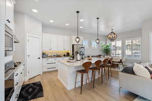 Kitchen with recessed lighting, a kitchen breakfast bar, an island with sink, light wood-style floors, and stainless steel appliances