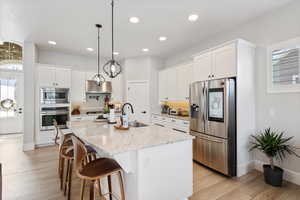 Kitchen featuring plenty of natural light, stainless steel appliances, light wood-style floors, white cabinetry, and recessed lighting