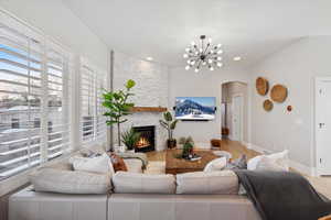 Living area featuring arched walkways, wood finished floors, a stone fireplace, a chandelier, and recessed lighting
