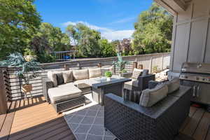 Wooden deck with an outdoor hangout area and a grill