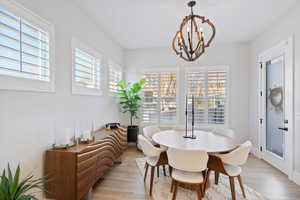 Dining space with healthy amount of natural light, a chandelier, and light wood-style floors