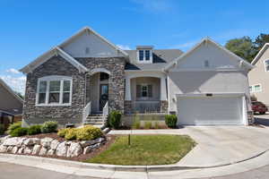 Craftsman house featuring concrete driveway, stone siding, a garage, and a porch