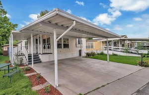 Covered porch with an attached carport and a lawn