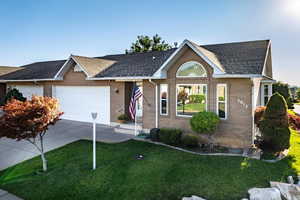 Ranch-style home featuring driveway, an attached garage, brick siding, and a front lawn