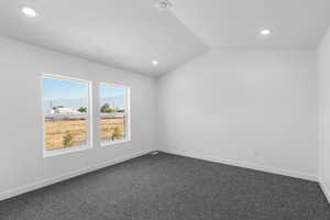Unfurnished room with vaulted ceiling, dark carpet, a mountain view, and recessed lighting
