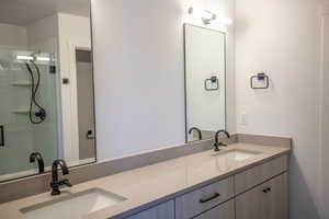 Full bath featuring double vanity and a stall shower
