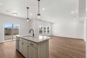 Kitchen featuring plenty of natural light, recessed lighting, light wood-style floors, light countertops, and a center island with sink
